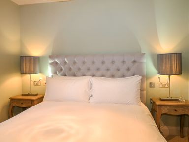 A bedroom with a bed with a tufted headboard two white pillows two bedside tables and two lamps at Moles Cottage in Farnham near Sixpenny Handley