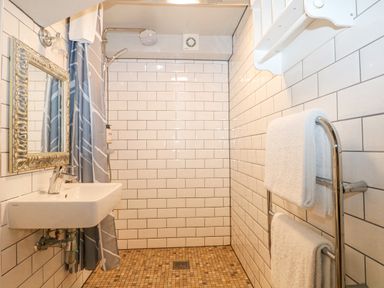A bathroom with a shower area a wall-mounted sink a mirror and towels on a rack at Moles Cottage in Farnham near Sixpenny Handley