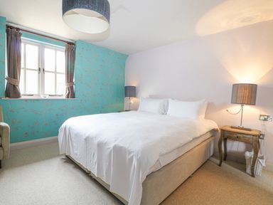A bedroom with a double bed bedside tables lamps and a window at Moles Cottage Farnham near Sixpenny Handley