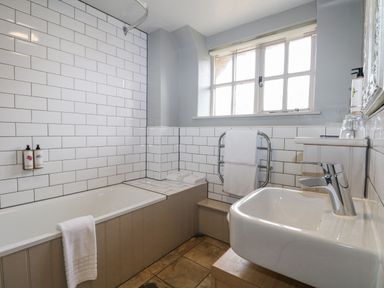 A bathroom with a bathtub towel rail sink and window at Moles Cottage in Farnham near Sixpenny Handley