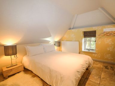 A bedroom with a double bed bedside tables lamps a window and hangers on the wall at Moles Cottage Farnham near Sixpenny Handley