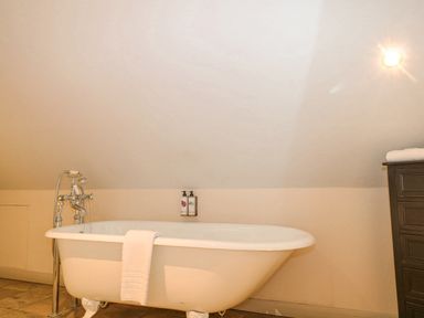 A bathroom with a clawfoot bathtub a towel hanging over the side and toiletries on the wall at Moles Cottage Farnham near Sixpenny Handley