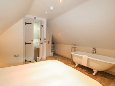 A bedroom with a clawfoot bathtub near an open door leading to a bathroom at Moles Cottage Farnham near Sixpenny Handley