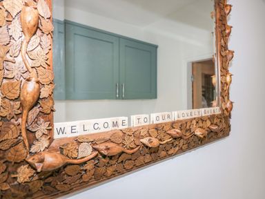A wooden framed mirror with scrabble tiles spelling welcome to our lovely guests at Elderflower Lodge in Allithwaite near Cartmel