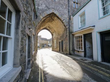 A narrow street with stone buildings and an arched passageway at Elderflower Lodge in Allithwaite near Cartmel