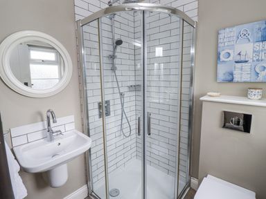 A bathroom with shower, sink, and mirror at Driftwood in 