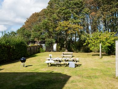 A garden with a picnic table and barbecue grill at Driftwood in Embleton