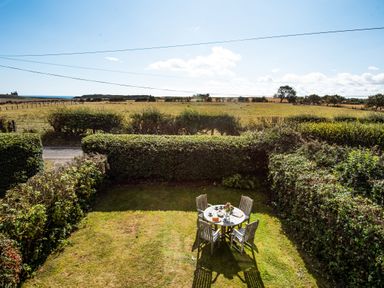 A garden with a table and chairs at Driftwood in Embleton