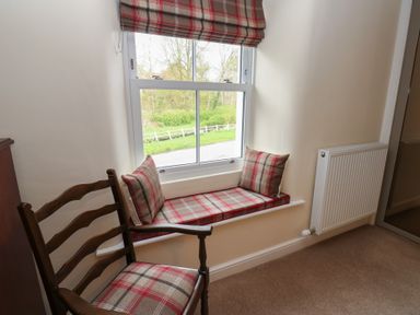 A sitting room with a window seat and chair at 1 Brookside in Warcop