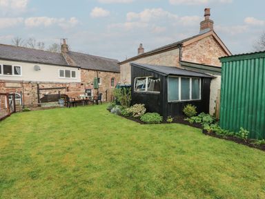A garden with a table and chairs and a shed at 1 Brookside Warcop