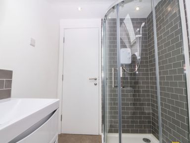 A bathroom with a glass shower enclosure and a white sink at Ty Chwarel in Menai Bridge