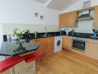 A kitchen with appliances and bar stools at Seaview in Benllech near Red Wharf Bay