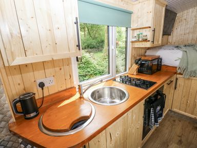 A kitchen with a sink and stove in a wooden cabin at The Hamper in Felingwm near Carmarthen