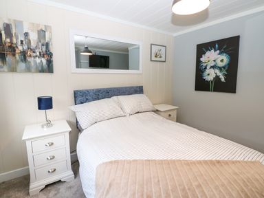 A bedroom with a bed between two bedside tables each with a lamp and wall art at Finnbars Lodge in Richmond