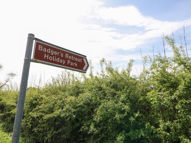 A road sign for Badger's Retreat Holiday Park next to green bushes under a blue sky at Finnbars Lodge in Richmond