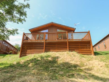 A log cabin with a deck on a hill at Finnbars Lodge in Richmond