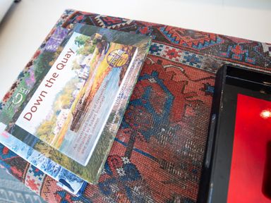 A close up of books stacked on a patterned fabric surface with a black tray at Curlew House in Cosheston