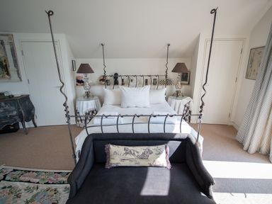 A bedroom with a four-poster bed two bedside tables with lamps and a sofa at Curlew House in Cosheston
