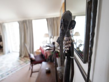 A dark wooden tribal sculpture with beads on a table in a living room at Curlew House in Cosheston