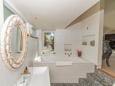 A bathroom with a bathtub sink and a seashell mirror at Curlew House in Cosheston