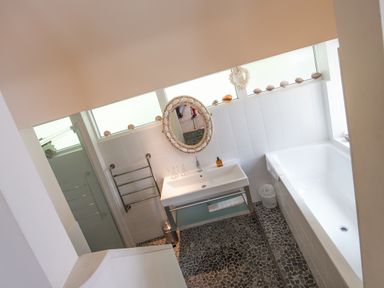 A bathroom with a bathtub sink round mirror and towel rack at Curlew House in Cosheston