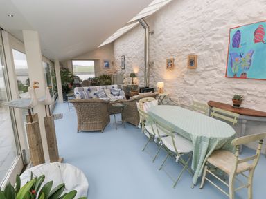 A conservatory with a dining table and couch at Curlew House in Cosheston
