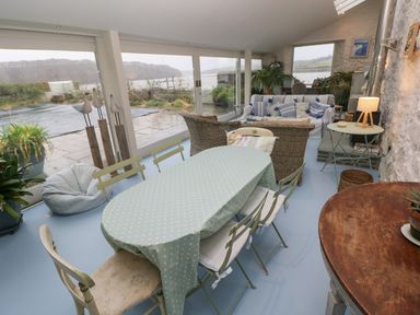 A conservatory with a table and chairs at Curlew House in Cosheston