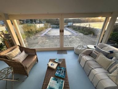 A conservatory with seating and a view of the patio at Curlew House in Cosheston