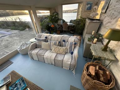 A conservatory with a sofa and plants at Curlew House in Cosheston