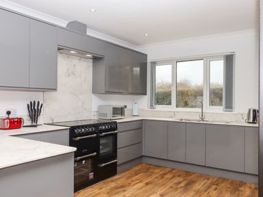 A kitchen with grey cabinets a black stove a microwave knife set red toaster and kettle at West View in Northlew near Hatherleigh