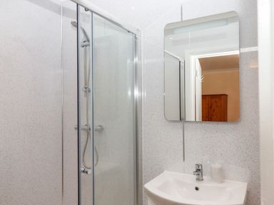 A bathroom with a shower enclosure and a sink with a mirror above it at West View in Northlew near Hatherleigh