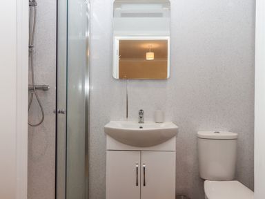 A bathroom with a shower, sink with cabinet, mirror, and toilet at West View in Northlew near Hatherleigh