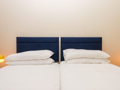 A bedroom with two single beds each with a blue headboard and white pillows and bedding at West View in Northlew near Hatherleigh
