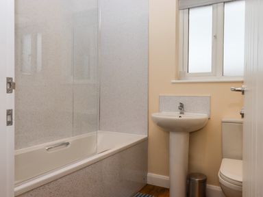 A bathroom with a bathtub a pedestal sink a toilet and a frosted window at West View in Northlew near Hatherleigh