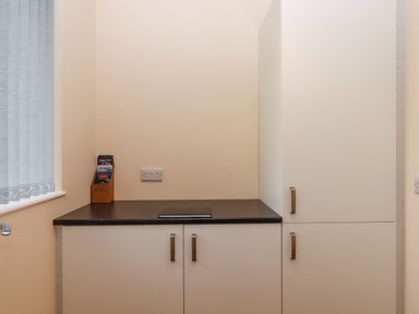A kitchen corner with a black countertop white cabinets vertical blinds on the window and a brochure holder at West View in Northlew near Hatherleigh