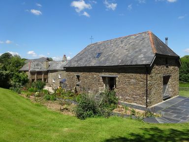 A stone house with a slate roof and garden in a grassy area at Swallows Reach in Halwell