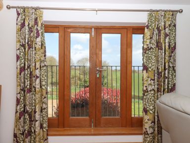 A window with curtains and garden view at Swallows Reach in Halwell