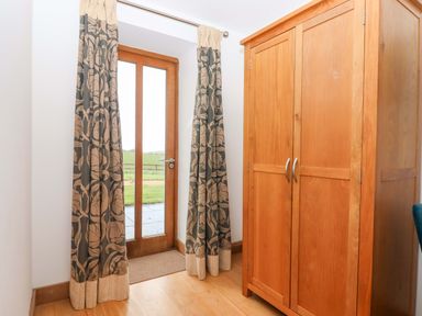 A hallway with curtains and a wooden wardrobe at Swallows Reach Halwell