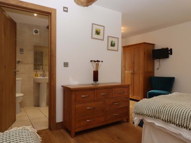A bedroom with a bed, dresser, and wardrobe at Swallows Reach Halwell