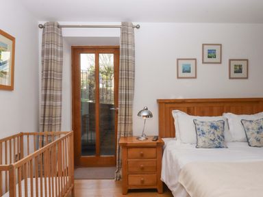 A bedroom with a crib and bed at Swallows Reach Halwell