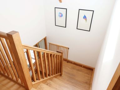 A staircase with wooden handrail and artwork at Swallows Reach Halwell