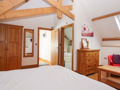 A bedroom with wooden furniture and a mirror at Swallows Reach Halwell