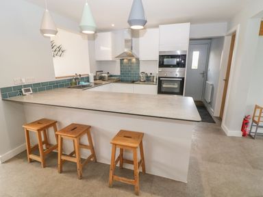 A kitchen with a countertop and wooden stools at Forest Lodge in Newborough