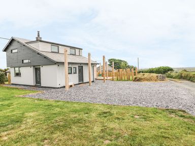 A two-story house with gravel driveway and lawn at Forest Lodge in Newborough