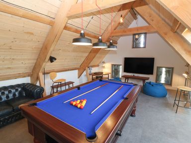 A games room with a pool table blue bean bags and a wall mounted television at Tithe Barn in Capel Mawr near Malltraeth