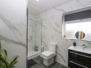 A bathroom with a shower enclosure toilet sink and window at Meillion in Hirwaun