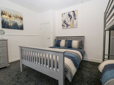 A bedroom with a double bed bunk bed dresser and two abstract paintings at Meillion in Hirwaun