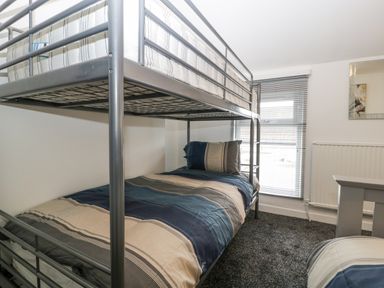 A bedroom with a metal bunk bed a window with blinds and a radiator at Meillion in Hirwaun