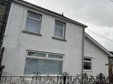 A white building with three windows and a black wrought iron fence in front at Meillion in Hirwaun