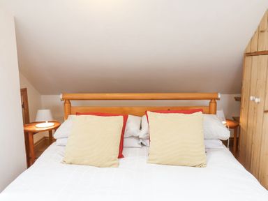 A bedroom with a double bed pillows side tables with lamps and wooden wardrobe at The Barn - Poplar Farm in Lower Dunsforth near Boroughbridge